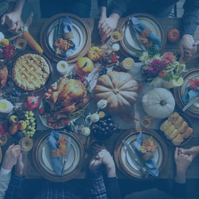 An overhead photo of a family at a dinner table enjoying a thanksgiving feast.