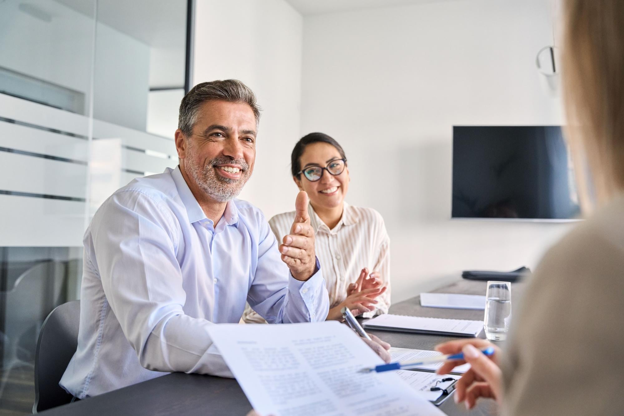 A professional translator and banker smiling and chatting with a client at a desk.